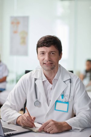 Téléchargez les photos : Portrait d'un médecin généraliste souriant travaillant au maximum dans un cabinet médical - en image libre de droit