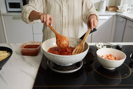 Foto de Mujer cocinando salsa de tomate caliente para espaguetis - Imagen libre de derechos