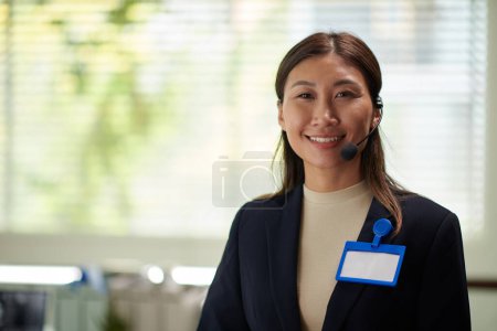 Téléchargez les photos : Portrait de femme d'affaires positive avec badge vide sur veste souriant à la caméra - en image libre de droit