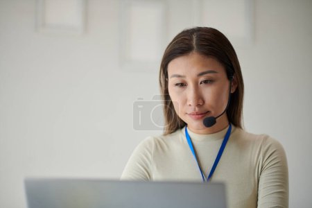 Téléchargez les photos : Portrait de femme d'affaires élégante portant un casque lorsque vous travaillez sur un ordinateur portable - en image libre de droit