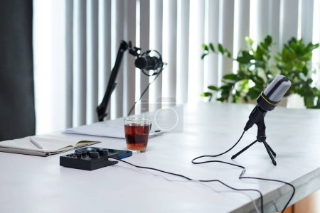 Téléchargez les photos : Microphones, amplificateur et tasse de thé noir sur la table prêts pour l'enregistrement podcast - en image libre de droit