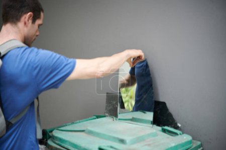 Photo for Young man collecting broken mirror for recycling or to make artwork from glass - Royalty Free Image