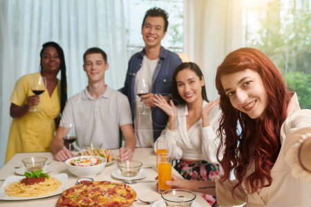 Téléchargez les photos : Positif cheveux roux jeune femme photographier avec des amis au dîner - en image libre de droit