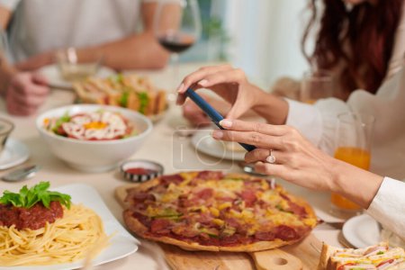 Téléchargez les photos : Mains de femme prenant des photos de nourriture sur la table du dîner - en image libre de droit