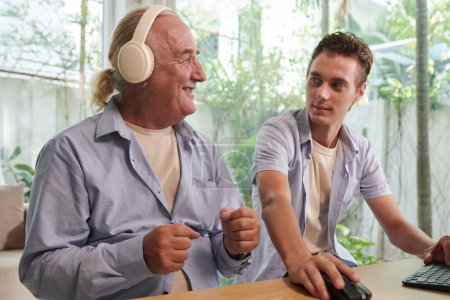 Photo for Young man sharing music playlist with grandfather - Royalty Free Image
