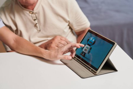 Téléchargez les photos : Fils installation assistant personnel sur tablette informatique du père aîné - en image libre de droit
