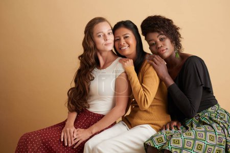Téléchargez les photos : Groupe diversifié de jeunes femmes souriantes appuyées l'une sur l'autre - en image libre de droit