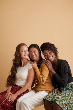 Foto de Retrato de estudio de jóvenes amigas felices apoyadas una en la otra cuando fotografian en el estudio - Imagen libre de derechos
