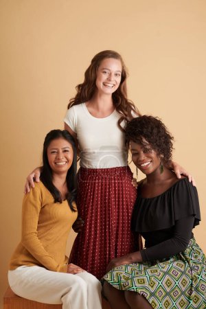 Téléchargez les photos : Jeune femme souriante debout à côté de ses deux meilleures amies, isolée sur beige - en image libre de droit