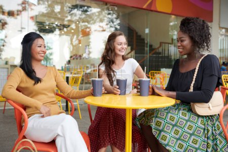 Foto de Diverso grupo de amigas que se reúnen en la cafetería al aire libre para tomar unas copas y discutir noticias - Imagen libre de derechos