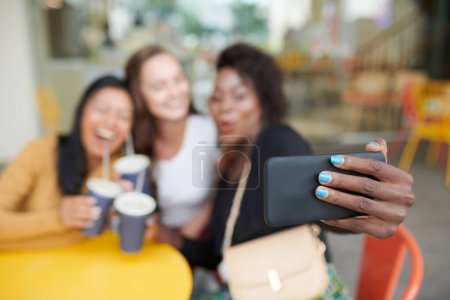 Téléchargez les photos : Femme avec vernis à ongles bleu vif prenant selfie avec les meilleurs amis dans le café, mise au point sélective - en image libre de droit