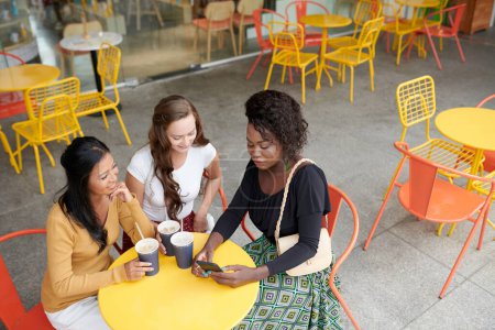 Photo for Group of female friends sitting at cafe table, drinking iced tea and discussing news and trends - Royalty Free Image