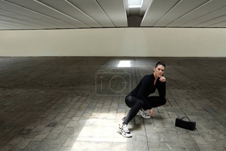 Téléchargez les photos : S'adapter jeune sportive ou danseuse posant dans un garage souterrain vide - en image libre de droit