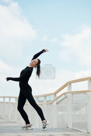 Téléchargez les photos : Happy slim fit danseuse de ballet féminine appréciant danser sur le pont - en image libre de droit