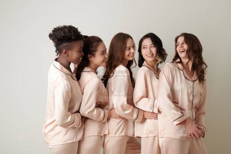 Téléchargez les photos : Groupe d'amies joyeuses en pyjama de soie debout l'une derrière l'autre - en image libre de droit