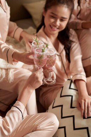 Téléchargez les photos : Amis féminins cliquetis verres de cocktails sucrés lors de la soirée pyjama à la maison - en image libre de droit
