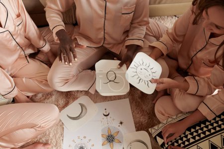 Téléchargez les photos : Femme expliquant comment l'astrologie tableau de naissance fonctionne à ses amis à la soirée pyjama - en image libre de droit