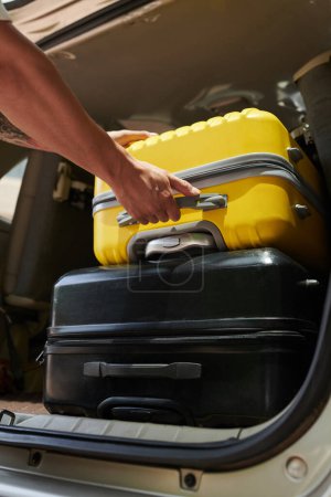 Foto de Imagen de primer plano del conductor del traslado al aeropuerto sacando las maletas del maletero del coche - Imagen libre de derechos