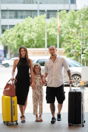 Téléchargez les photos : Famille heureuse avec des suites entrant dans un hôtel de luxe - en image libre de droit