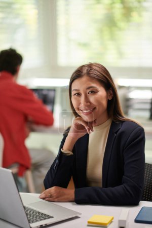 Téléchargez les photos : Femme d'affaires positive travaillant sur ordinateur portable au bureau - en image libre de droit
