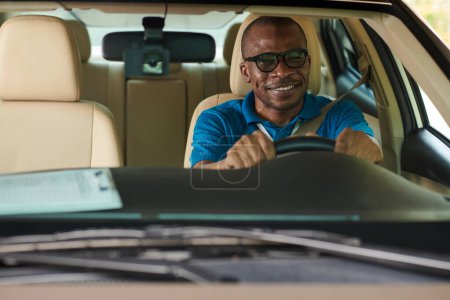 Téléchargez les photos : Joyeux mais inquiet homme noir transpirant voiture de conduite pour la première fois - en image libre de droit
