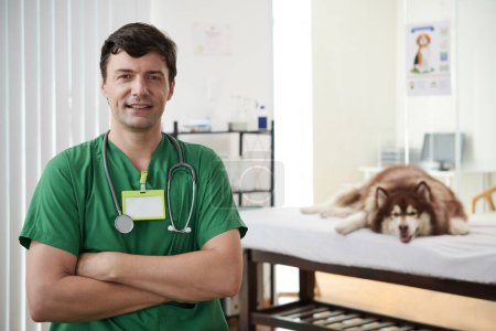Téléchargez les photos : Portrait d'un vétérinaire souriant debout dans une salle d'examen les bras croisés - en image libre de droit