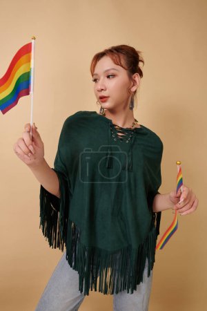 Téléchargez les photos : Jeune femme transgenre posant avec deux drapeaux arc-en-ciel, concept de mois de fierté - en image libre de droit