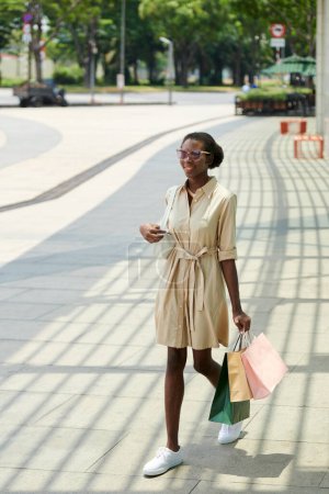 Téléchargez les photos : Joyeux jeune femme avec de nombreux sacs à provisions marchant dans la rue, concept d'activités de week-end - en image libre de droit