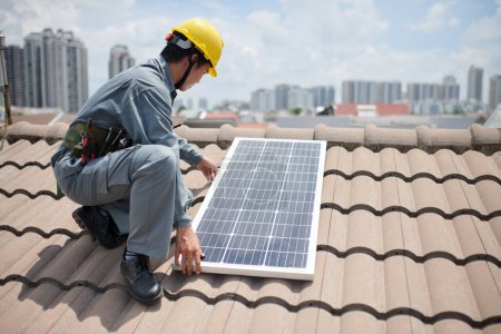 Foto de Imagen recortada del trabajador instalando paneles solares en el techo del edificio residencial - Imagen libre de derechos