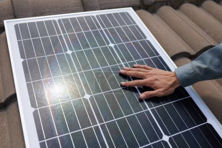Foto de Mano del contratista tocando el panel solar en el techo, concepto de energía alternativa - Imagen libre de derechos