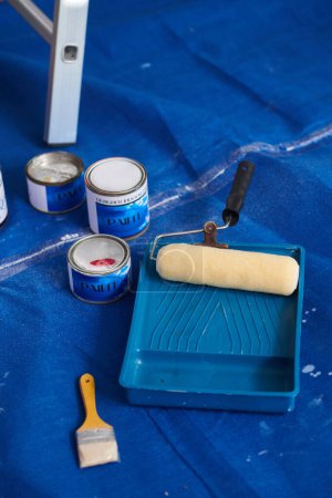 Photo for Paint tray, rollers and cans of interior paints of floor covered with textile - Royalty Free Image