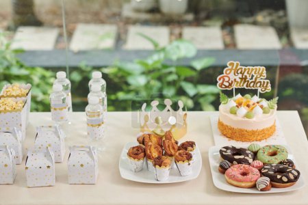 Téléchargez les photos : Délicieuses friandises, bouteilles d'eau et petits invités pour les invités de fête d'anniversaire - en image libre de droit