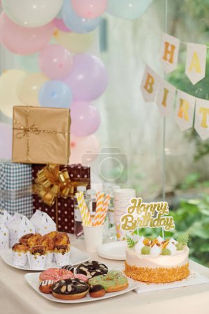 Téléchargez les photos : Gâteau d'anniversaire et bonbons à côté de cadeaux sur la table senrved pour la fête - en image libre de droit