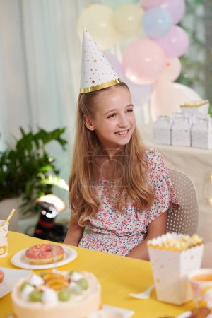 Foto de Retrato de una chica sonriente comiendo dulces en la fiesta de cumpleaños - Imagen libre de derechos