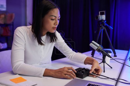Téléchargez les photos : Blogueuse mettant le cordon de microphone dans l'amplificateur pour obtenir un meilleur son pour son podcast - en image libre de droit