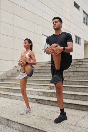 Téléchargez les photos : Jeune couple étirant les jambes pour se réchauffer avant de courir - en image libre de droit