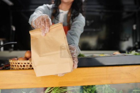 Foto de Trabajador de camión de alimentos con guantes que dan paquete de papel con orden cocinada - Imagen libre de derechos