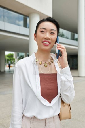 Téléchargez les photos : Portrait d'une jeune femme d'affaires positive répondant à un appel téléphonique d'un collègue - en image libre de droit