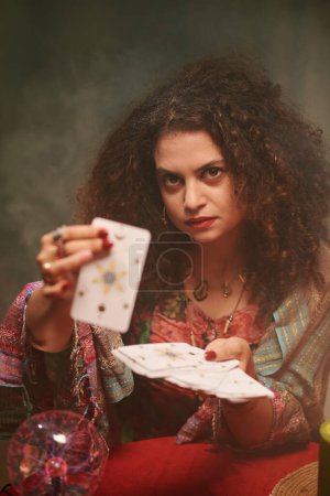 Photo for Portrait of serious sorcerer showing tarot cards, fortune telling concept - Royalty Free Image