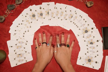Photo for Hands of fortune teller with many rings and spred tarot cards, view from above - Royalty Free Image