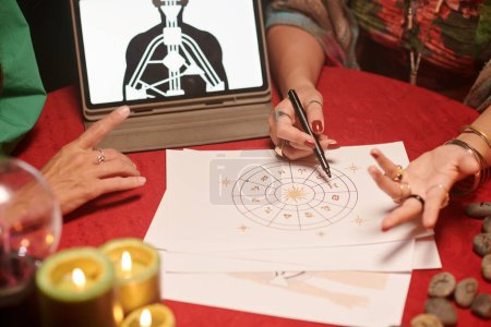 Téléchargez les photos : Astrologue analysant le tableau natal de la cliente et lui donnant des conseils - en image libre de droit