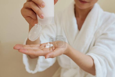 Téléchargez les photos : Image en gros plan de la lotion hydratante à la main pour hydrater la peau après la douche - en image libre de droit