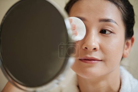Téléchargez les photos : Jeune femme démaquillant les yeux avec du coton imbibé d'eau micellaire - en image libre de droit