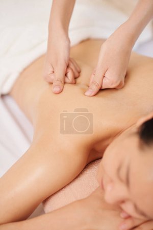 Photo for Hands massaging upper back of young female client - Royalty Free Image
