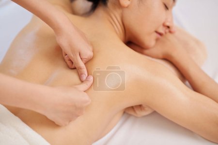 Foto de Masajista dando masaje de espalda de tejido profundo a joven cliente femenino - Imagen libre de derechos