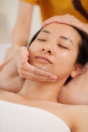 Photo for Young Asian woman enjoying anti-ageing and lifting face massage - Royalty Free Image
