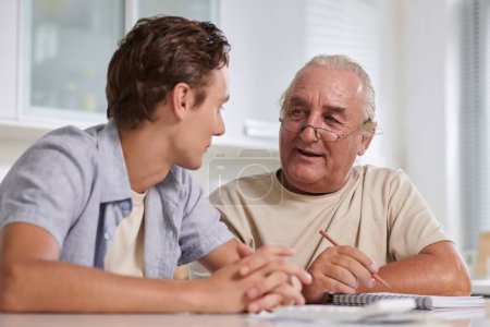 Photo for Smiling senior man telling teenage grandson how to manage personal finances - Royalty Free Image
