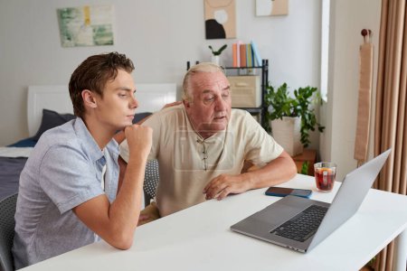 Photo for Grandfather and grandson watching video on laptop together - Royalty Free Image