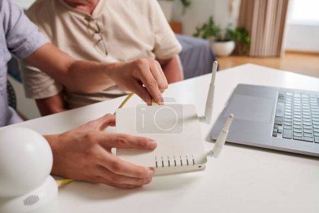 Photo for Hands of young man inserting cord in router when setting up wi-fi network in house of father - Royalty Free Image