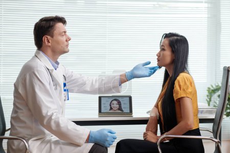 Téléchargez les photos : Chirurgien plasticien examinant le visage du patient avant d'injecter un traitement anti-âge - en image libre de droit